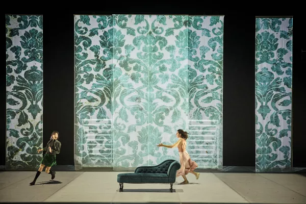 Photo du spectacle Roméo et Juliette, vue de toute la scène avec un décor coloré en bleu et deux comédiennes sur scène qui marchent